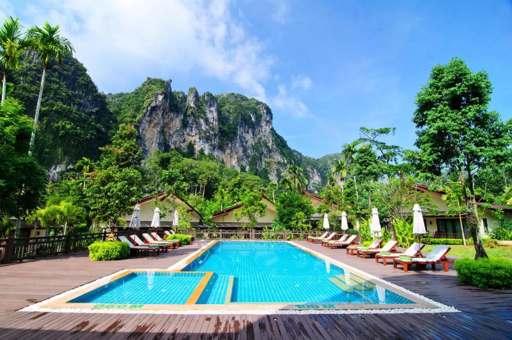 a resort swimming pool with chairs and a mountain in the background at Aonang Phu Petra Resort, Krabi - SHA Plus in Ao Nang Beach