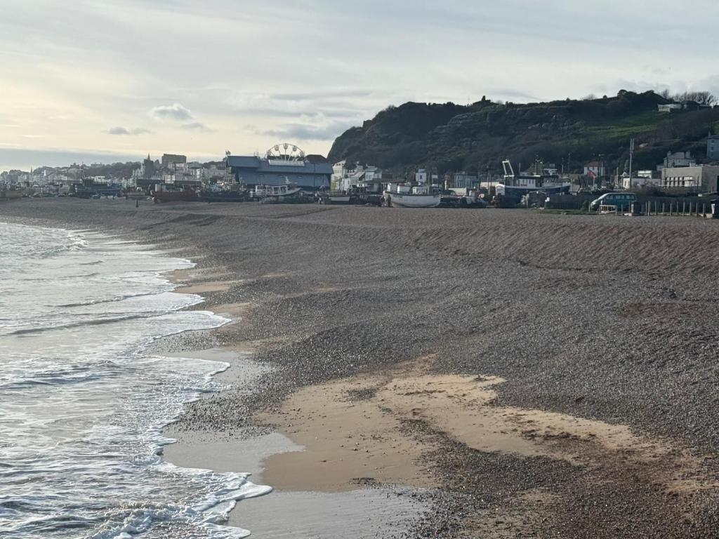 ein Sandstrand mit einer Stadt im Hintergrund in der Unterkunft Sullys in Hastings
