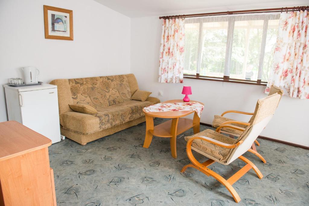 uma sala de estar com um sofá, uma mesa e cadeiras em Ośrodek Wypoczynkowy Wagabunda em Mikolajki