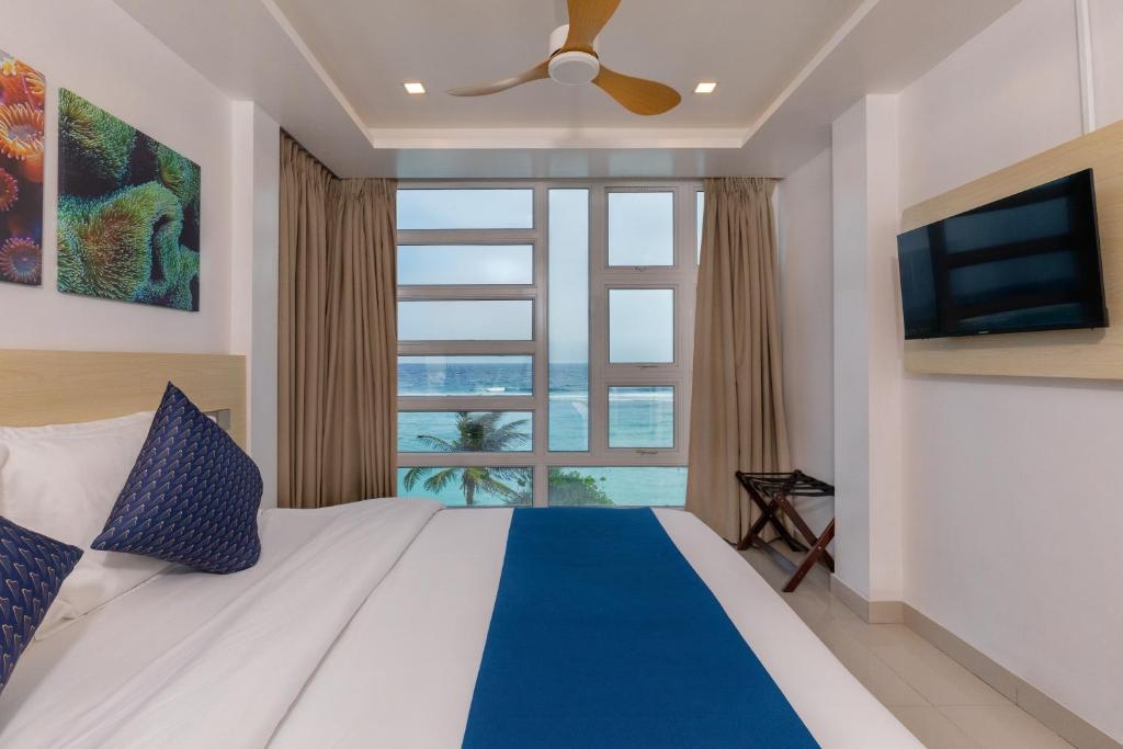 a bedroom with a bed with a ceiling fan and a window at White Harp Beach in Hulhumale