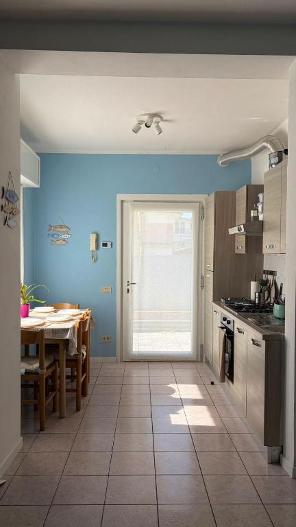 a kitchen with a table and a blue wall at Beach 300m Piazza Milano in Lido di Jesolo