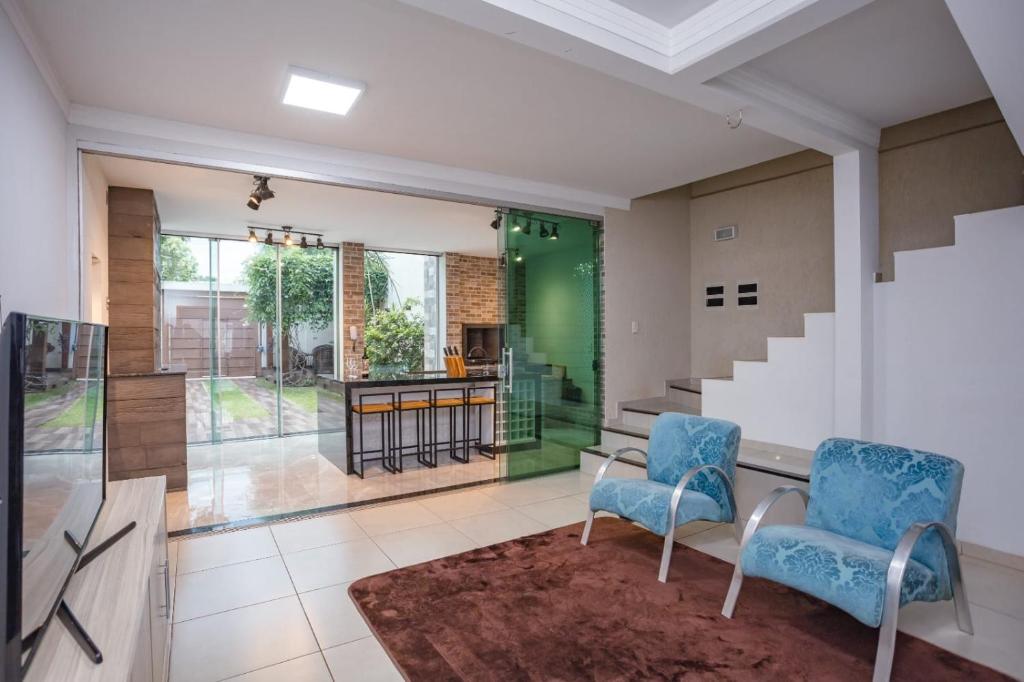 a living room with two chairs and a table at Sobrado Jardim Real in Maringá
