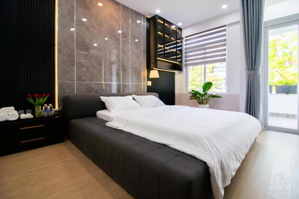 a bedroom with a large bed with a black couch at An Nhiên House in Kon Rung (1)