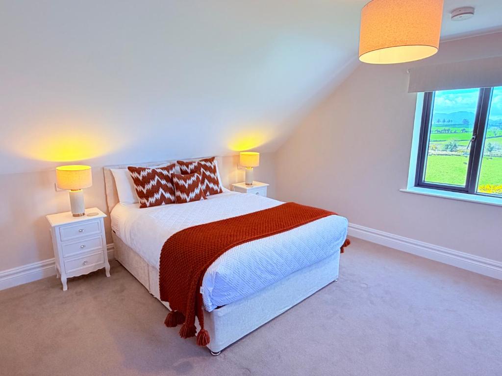a bedroom with a bed with two lamps and a window at Country View House in Milltown