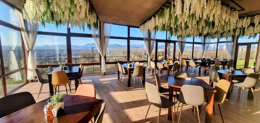 a restaurant with tables and chairs and large windows at Хотел Магура in Rabisha