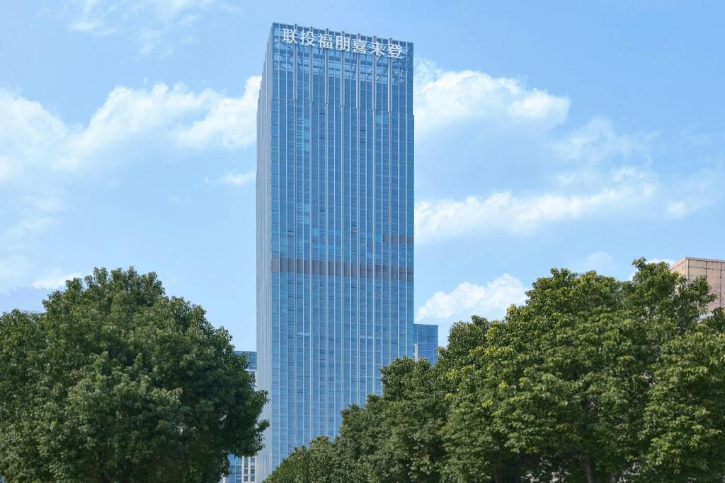 a tall glass building with trees in front of it at Four Points by Sheraton Wuhan, Jiangxia in Wuhan