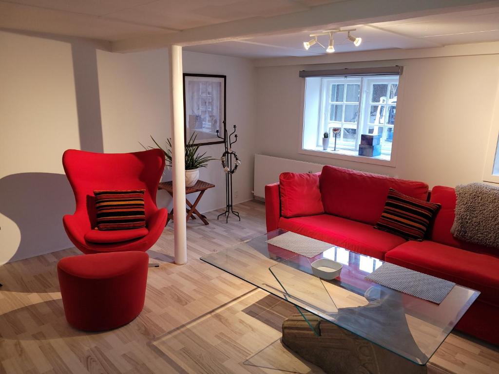 a living room with a red couch and a glass table at Gamle Præstegård, viceværtlejlighed in Årup