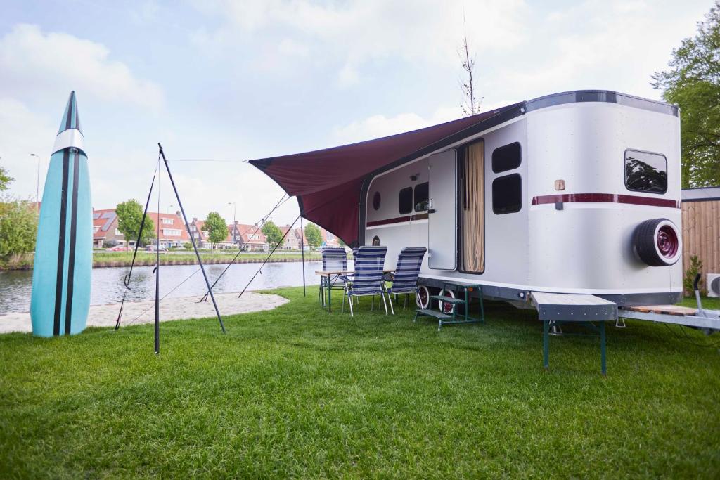 a white trailer with a canopy on the grass at Glampervan Julietta in Den Bosch