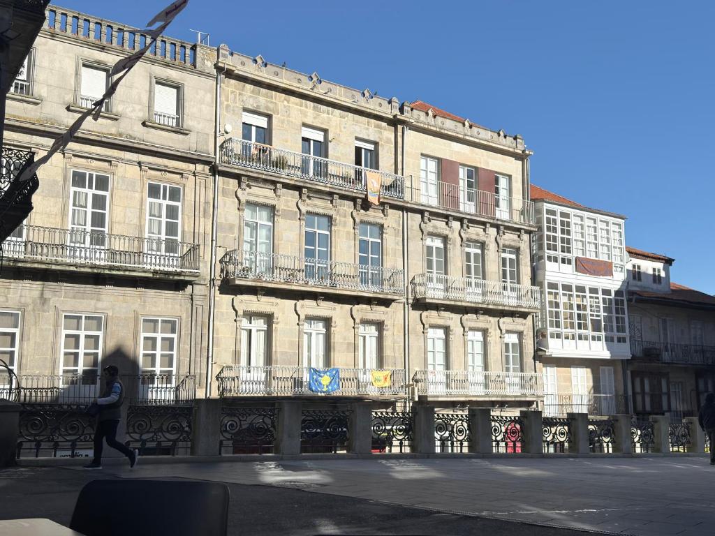 a person walking in front of a large building at APART_SANVICENTE 6 in Vigo