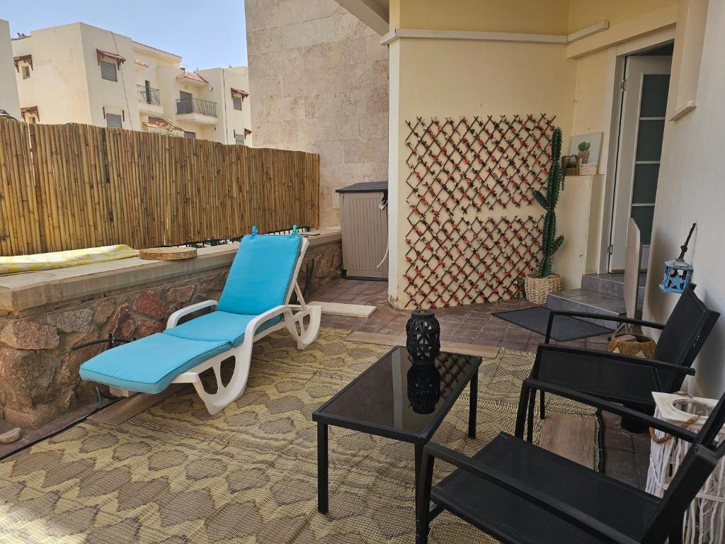 a patio with a blue chair and tables and a fence at Studio Caroline in Eilat