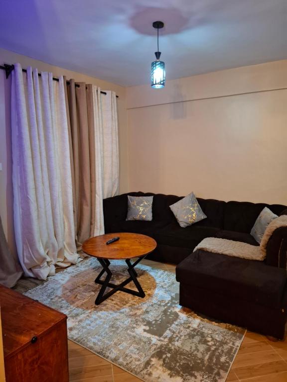 a living room with a black couch and a table at Baraka Stay,Kenol,Gitura,Murang'a in Gitura