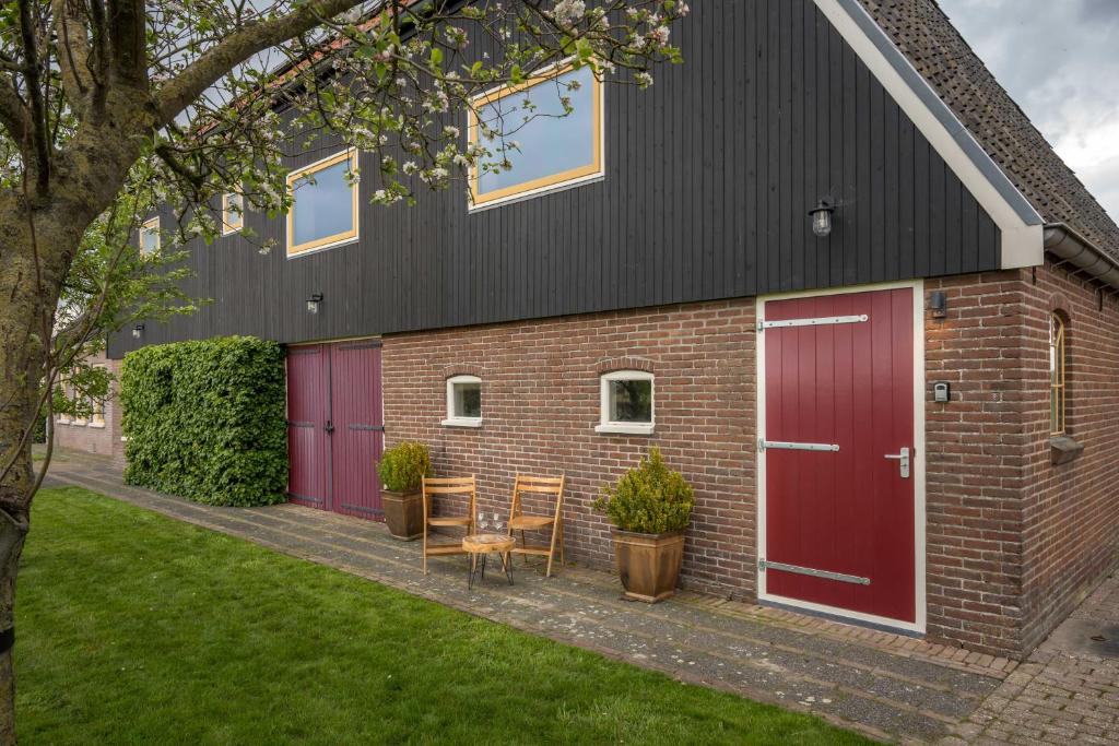 a brick building with red doors and chairs on a sidewalk at By de barte in Beers