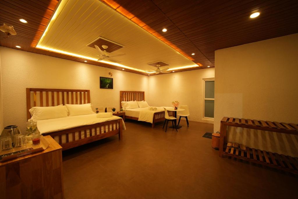 a bedroom with two beds and a couch and a table at Misty Garden Retreat in Nandigunda