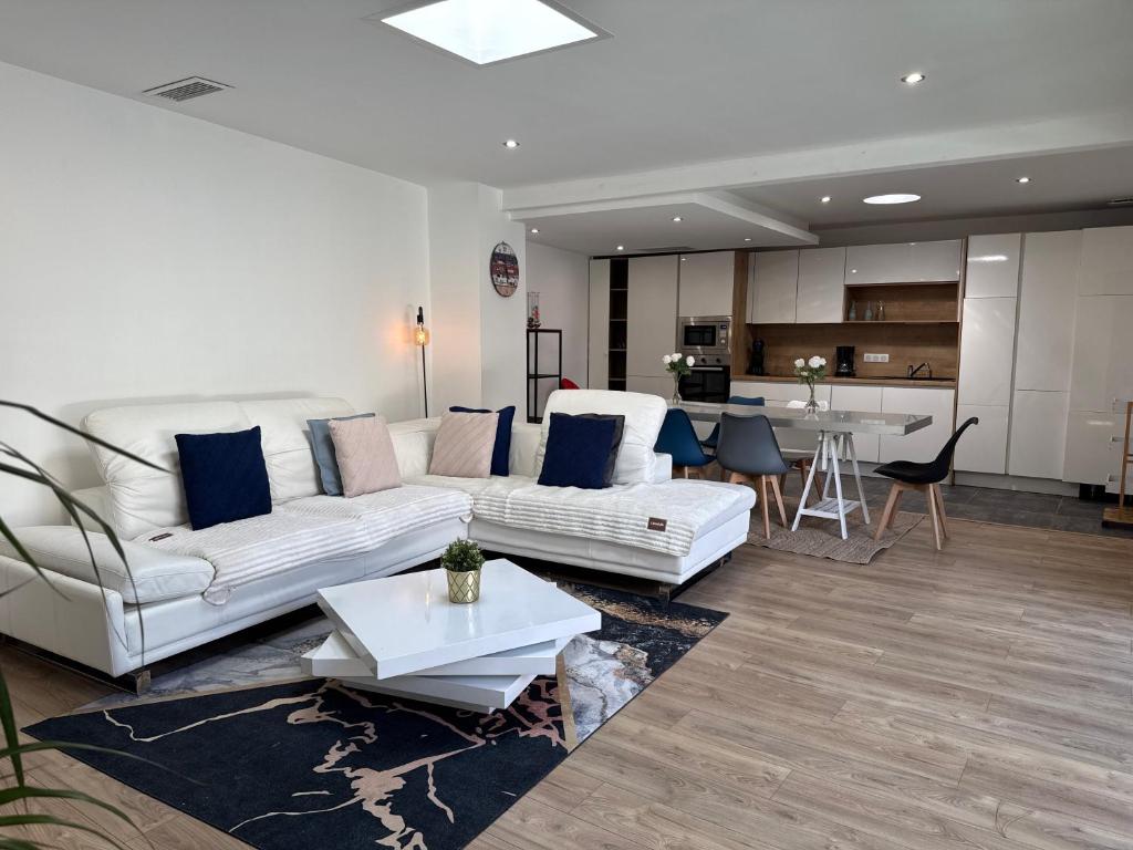 a living room with two white couches and a kitchen at Villa bord de mer in Labenne