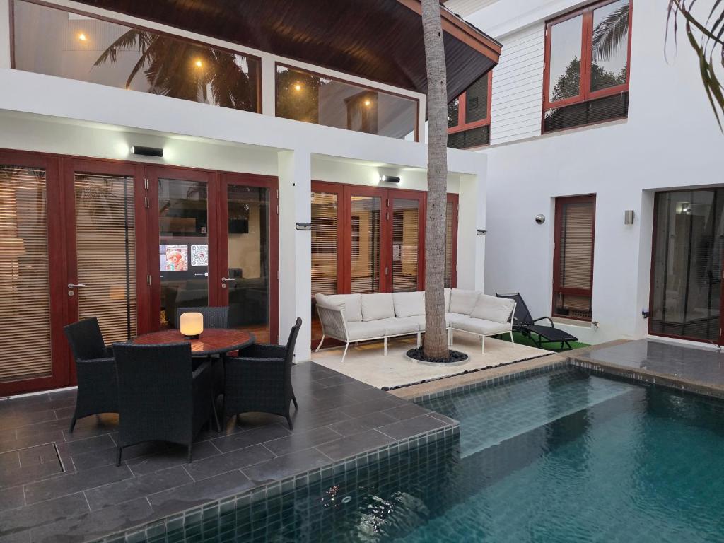 a house with a swimming pool with a table and chairs at Pranaluxe Pool Villa ORG in Pran Buri