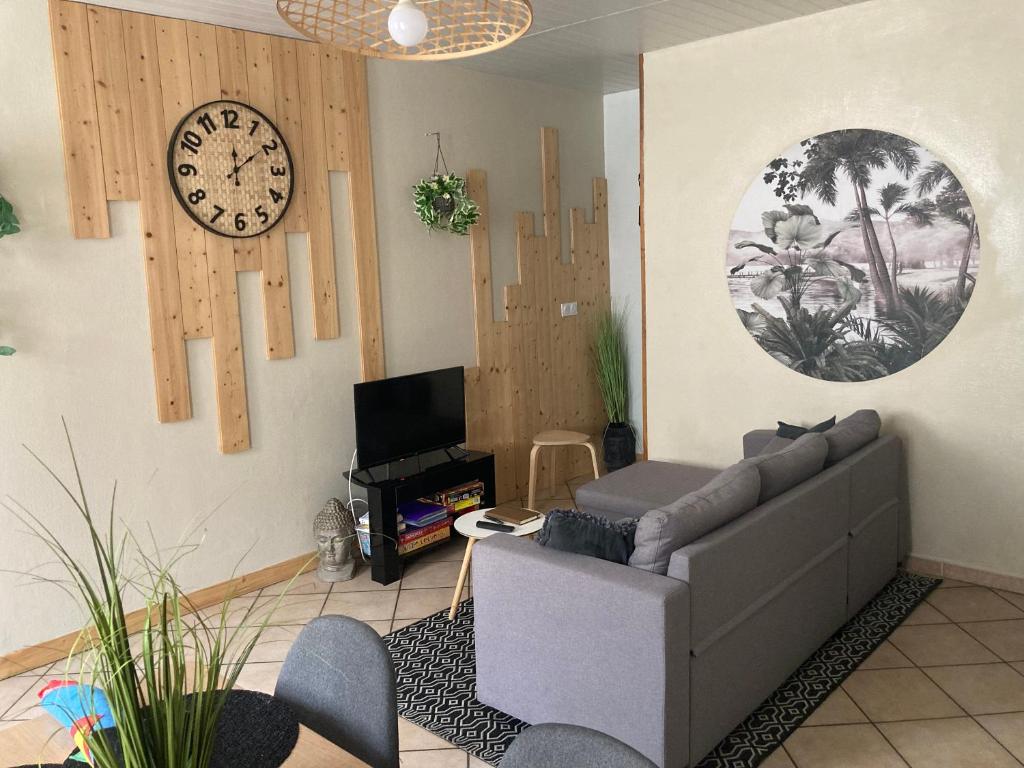a living room with a couch and a clock on the wall at Olivine , Chaleureuse & cocooning in Bogny Sur Meuse