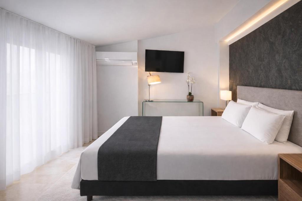 a hotel room with a large white bed and a television at Abril Nerja in Nerja