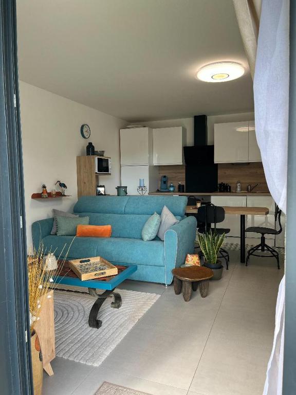 a living room with a blue couch and a kitchen at L'Appart'CASANELLA in Sarzeau