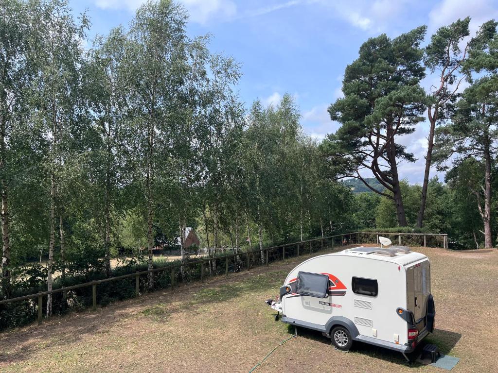 a white caravan parked in a field next to a fence at Camping pod in Greatham
