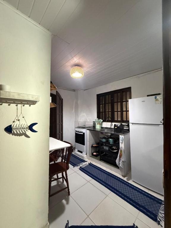 a kitchen with a white refrigerator and a table at Chalé com vista na vila centro histórico in Ilhabela