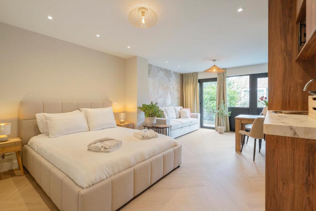 a bedroom with a white bed and a living room at Boetiek ManjaFiek in Zandvoort