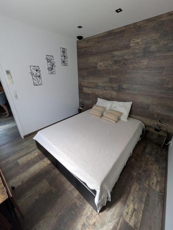 a bed in a room with a wooden wall at Chambre la Belle Étape in Martinet