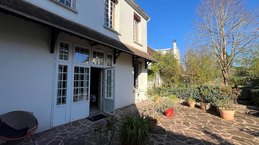 a white house with a courtyard with potted plants at Le Chanoine - Centre Ville - Sens in Sens