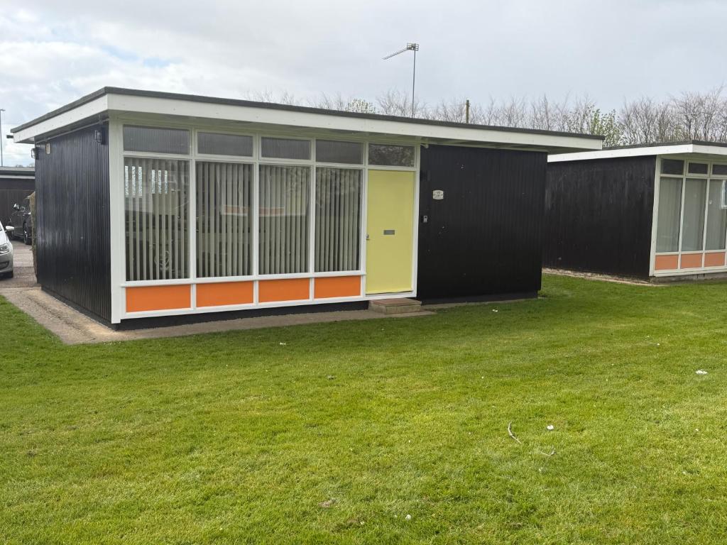 a small building with an orange and yellow front at 2 Broadside Chalet Park in Stalham