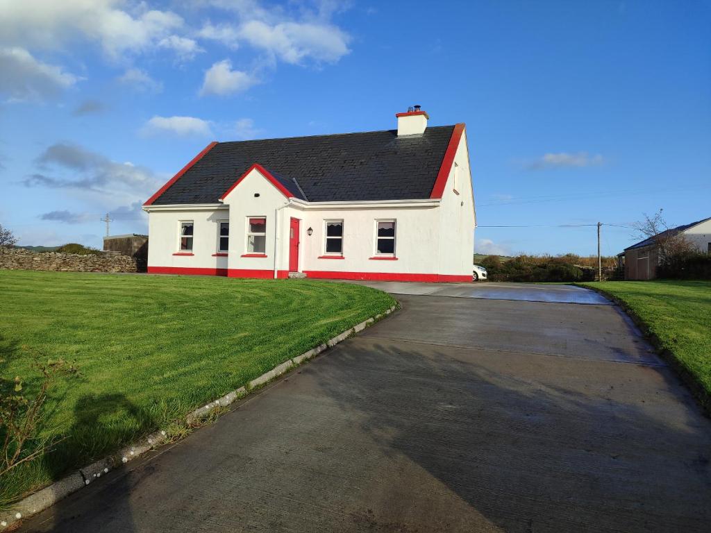 a white house with a black roof on a driveway at Gerry's house in Milltown Malbay