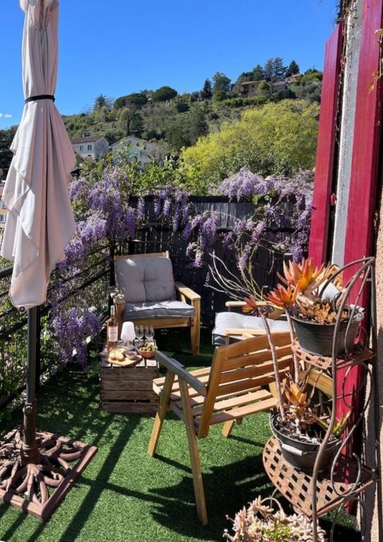 a garden with a bench and a chair and flowers at Les Capucines, comme chez soi, loin de chez soi in Aubenas