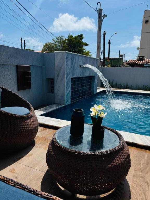 a pool with a table with flowers and a fountain at Labonita House - Pilar in Itamaracá
