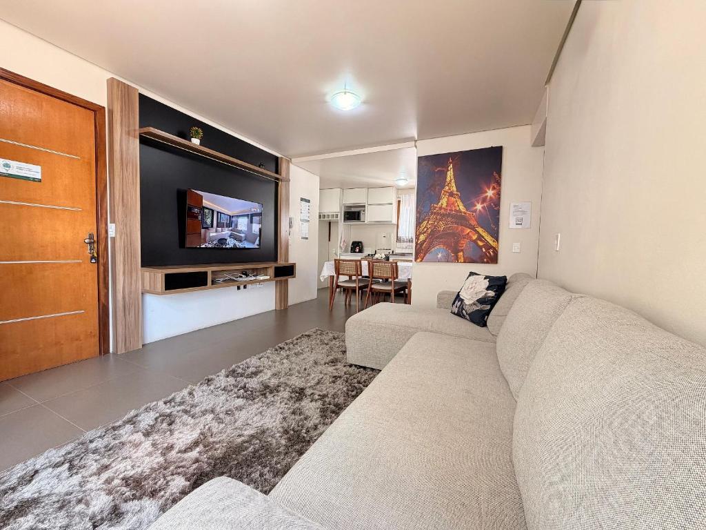 a living room with a couch and a flat screen tv at Apartamento Coração de Gramado in Gramado