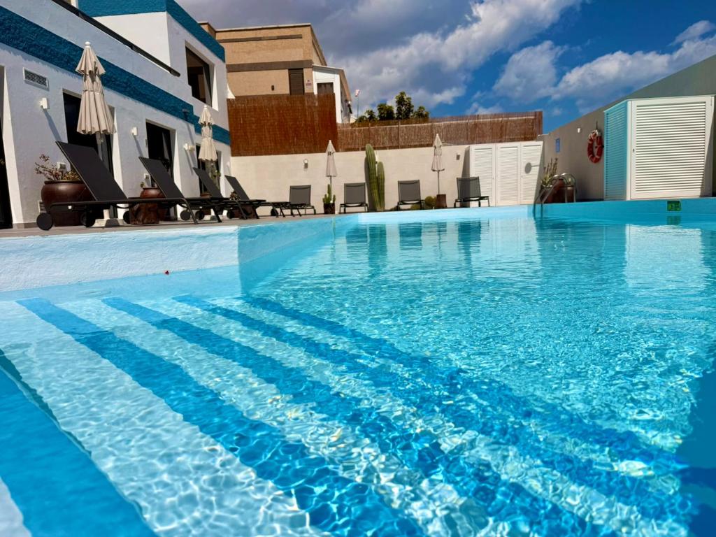 a large swimming pool with blue water in front of a building at Ocean Suite by SHC with heated pool only for adults in Telde