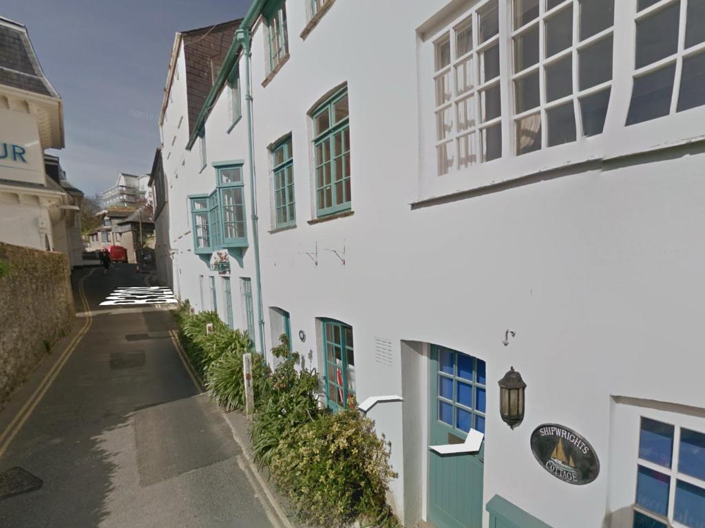 an alley with white buildings with blue windows at Shipwrights Cottage in Salcombe
