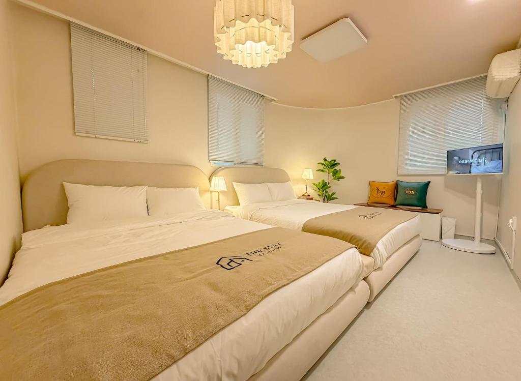 two beds in a room with windows and a chandelier at The Stay Gangnam COEX Hanti Station 5 minutes! 3Queen Bed in Seoul