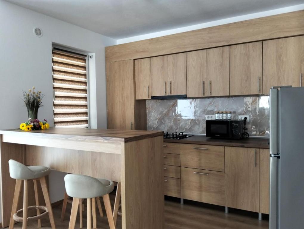 a kitchen with wooden cabinets and a counter with stools at GH Apartments 2 in Gura Humorului