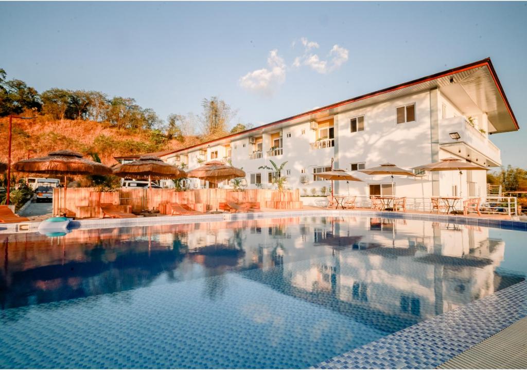 a swimming pool in front of a building with umbrellas at Kabesera Bed and Coffee in Binangonan