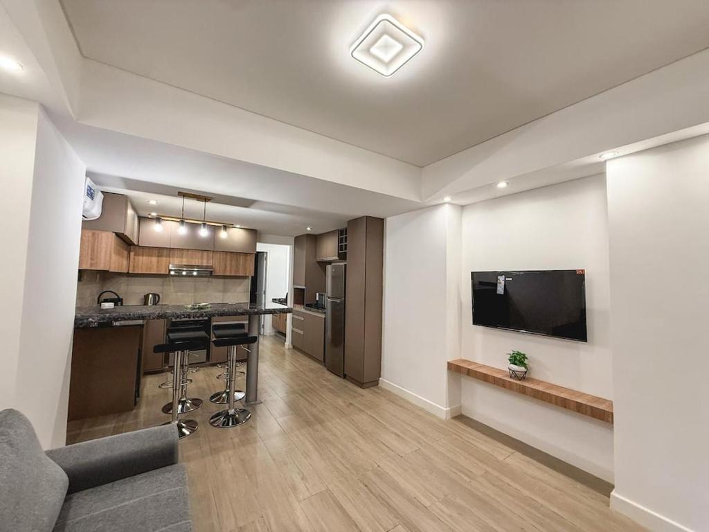 a large living room with a kitchen and a tv at Aura Urbana Apartment in San Juan