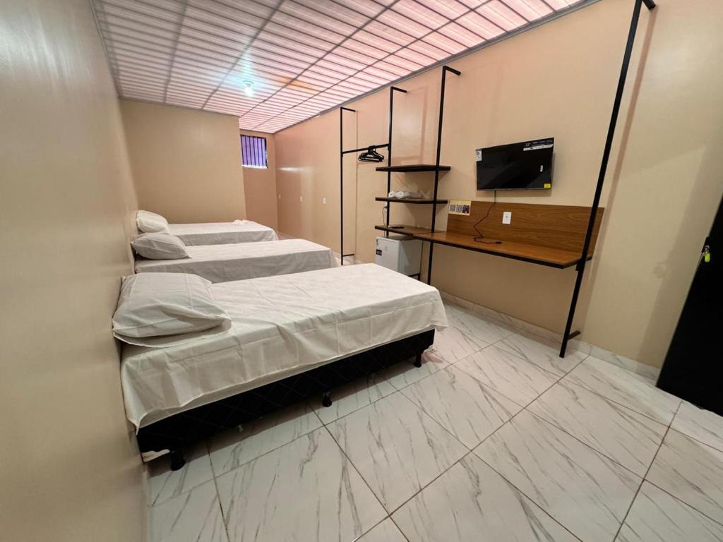a room with two beds and a television in it at Pousada G3 in Presidente Figueiredo