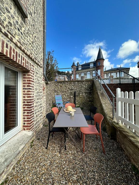 a patio with a table and chairs and a building at Manava Etretat Sea ViewHouse in Étretat