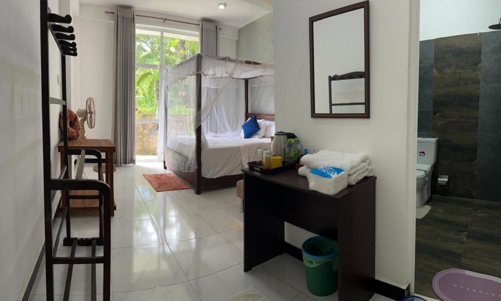 a bathroom with a bedroom with a bed and a desk at Ella Thenulya in Ella