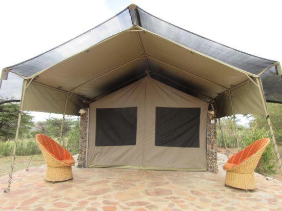 a tent with two chairs in front of it at Odupoi Lodge in Maji Moto