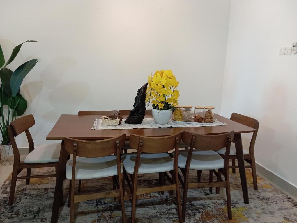 a dining room table with chairs and a vase of flowers at Seri Jerantut Homestay in Jerantut
