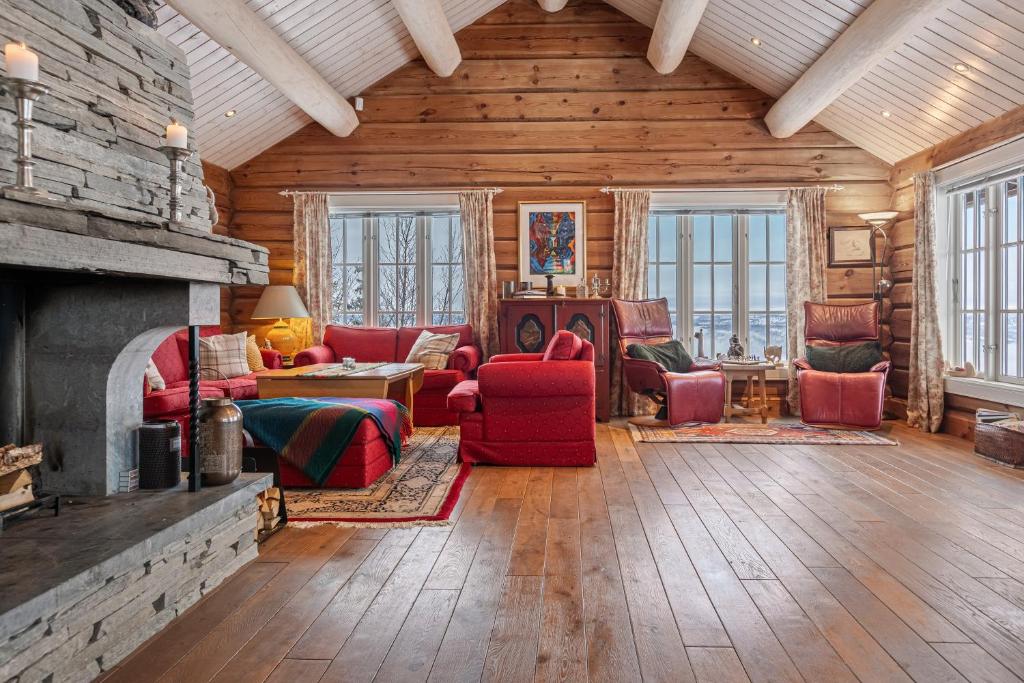 a living room with red furniture and a fireplace at Eksklusiv tømmerhytte Spa Panoramautsikt in Aurdal