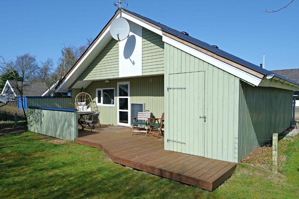 a green shed with a wooden deck in the yard at Bork Cozy Cottage in Hemmet