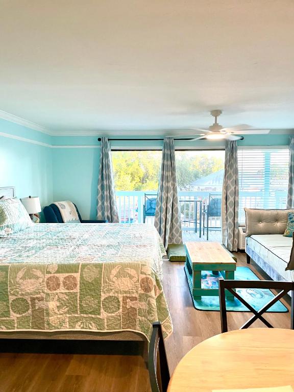 a bedroom with a bed and a couch and a window at Cedar Key Islands Dolphins Cay Condo in Cedar Key