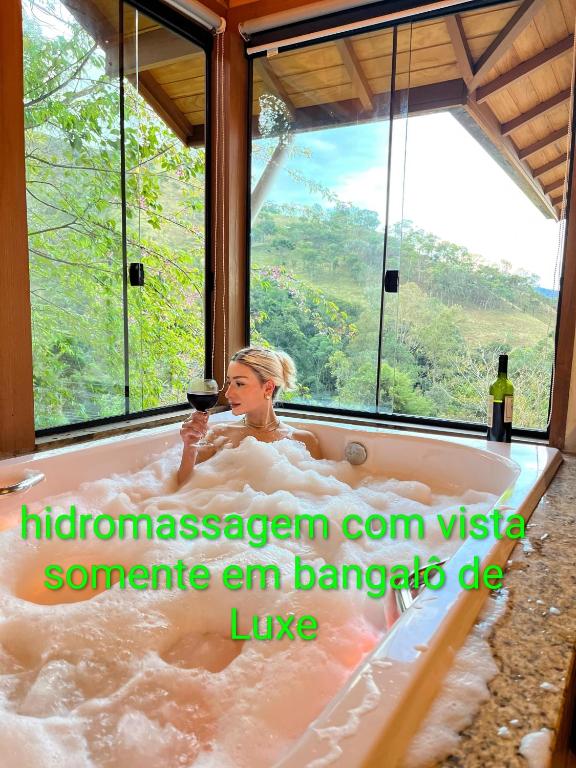 a woman sitting in a tub with a glass of wine at pousada caminho do escorrega in Visconde De Maua