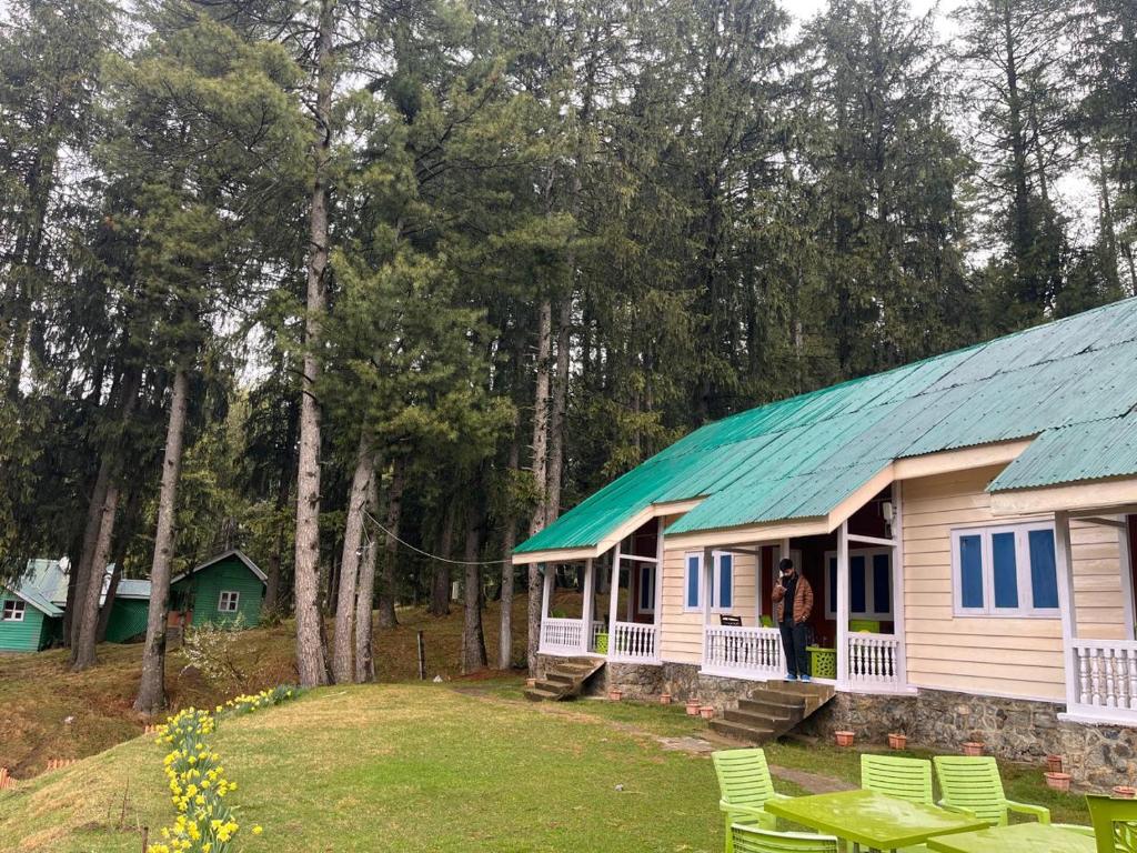a woman standing in front of a house with a green roof at Lala Ji coasy cottage in Pahalgām