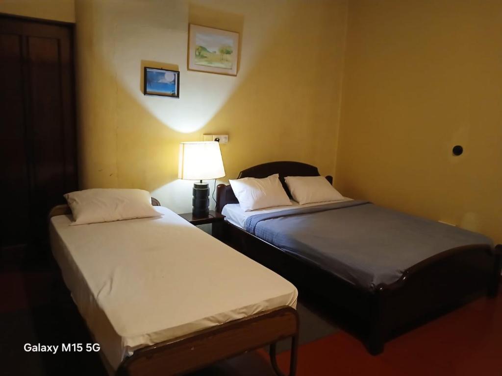 two beds in a hotel room with a lamp at Gleanloch Holiday Resort in Tawalantenna