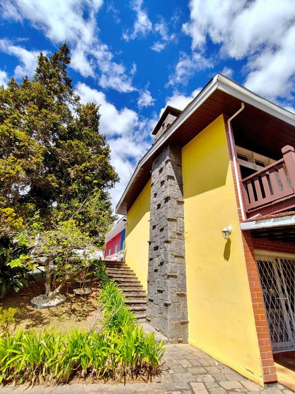 a house with a yellow door and stairs at Recanto MJ in Campos do Jordão